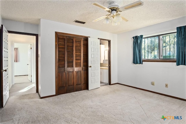 unfurnished bedroom featuring ceiling fan, a textured ceiling, a closet, and light carpet