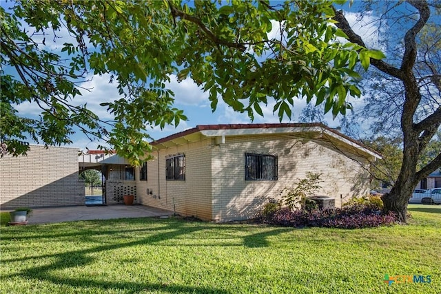 view of side of home featuring central AC unit, a patio area, and a lawn