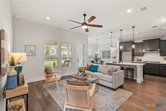 living room with ceiling fan, dark wood-type flooring, and sink