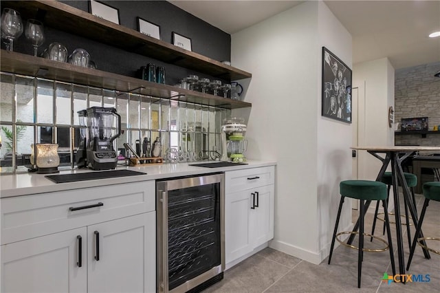 bar featuring a dry bar, light tile patterned floors, beverage cooler, and baseboards