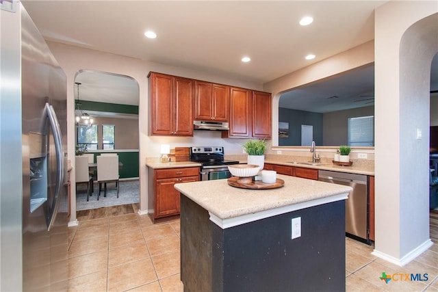 kitchen with sink, stainless steel appliances, light tile patterned floors, a notable chandelier, and a kitchen island