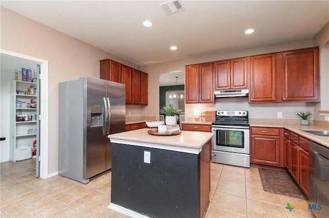 kitchen with stainless steel appliances, sink, a chandelier, a center island, and light tile patterned flooring