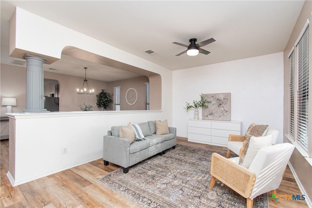 living room featuring ceiling fan with notable chandelier, decorative columns, and light hardwood / wood-style floors