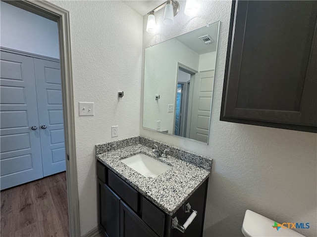 bathroom with wood-type flooring, vanity, and toilet