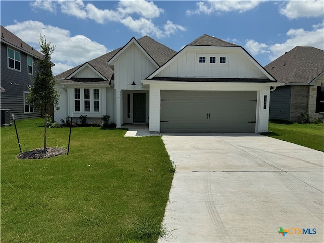 view of front of house with a front yard, central AC, and a garage