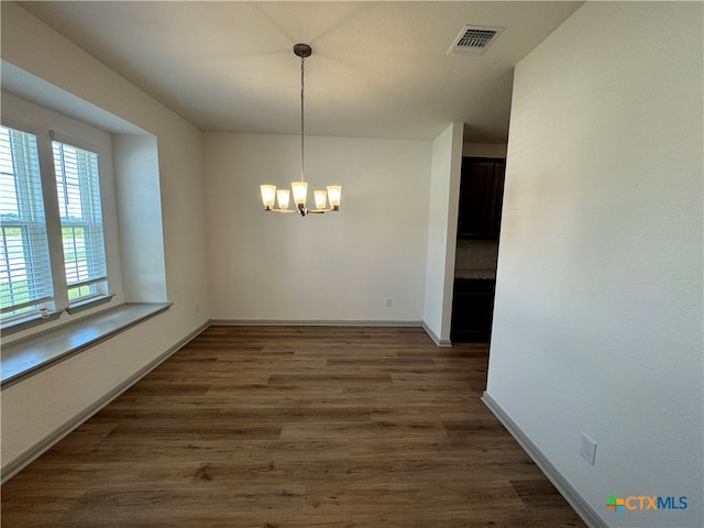 unfurnished dining area with an inviting chandelier and dark hardwood / wood-style floors