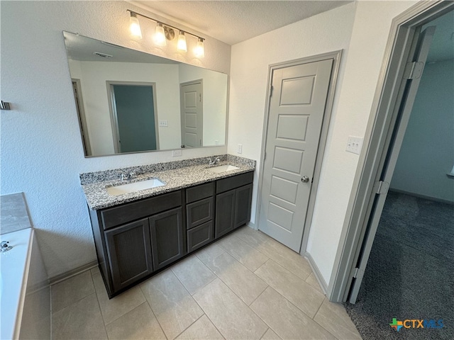 bathroom featuring tile patterned flooring, vanity, and a textured ceiling