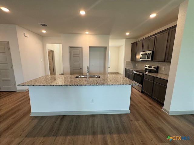 kitchen featuring dark wood-type flooring, appliances with stainless steel finishes, sink, and a center island with sink