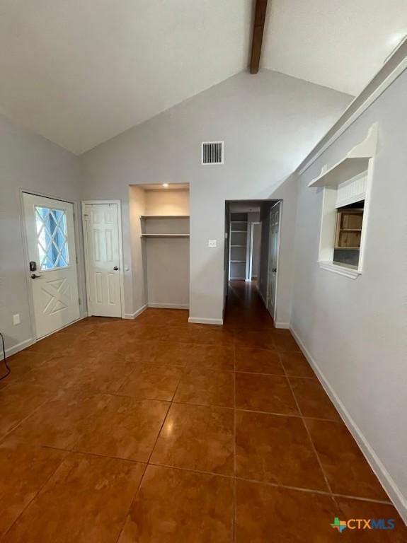 hall with dark tile patterned flooring, beam ceiling, and high vaulted ceiling