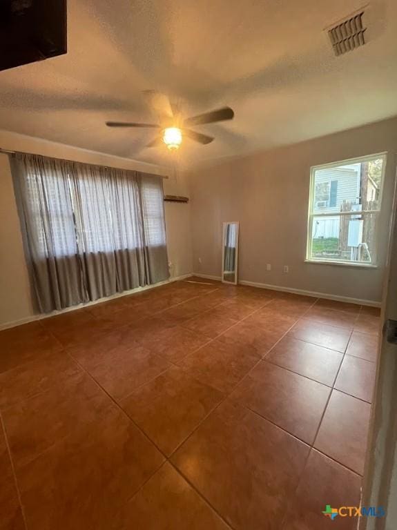 tiled spare room with ceiling fan