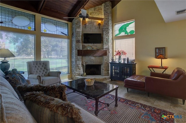 tiled living room with ceiling fan, high vaulted ceiling, wooden ceiling, and a stone fireplace