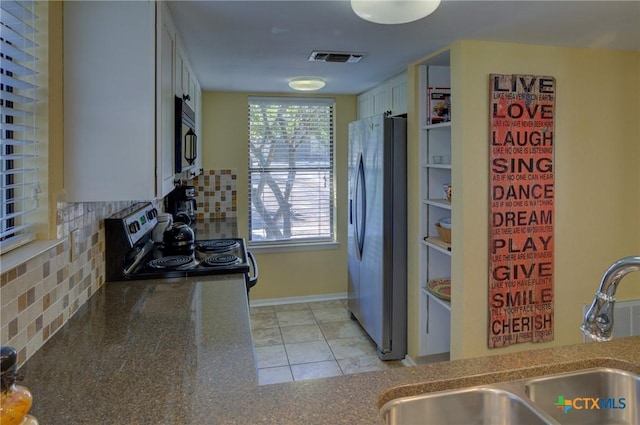 kitchen with white cabinets, stainless steel appliances, decorative backsplash, sink, and light tile patterned floors