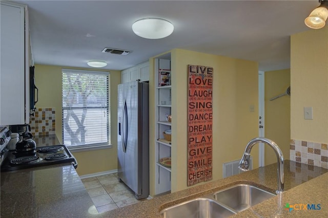 kitchen with black electric range oven, white cabinetry, decorative backsplash, sink, and stainless steel fridge