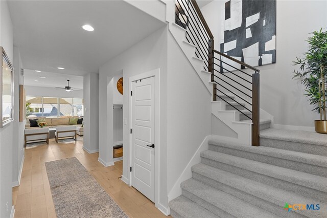 stairs featuring hardwood / wood-style flooring and ceiling fan