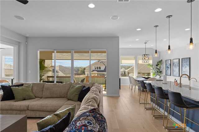 living room with light wood-type flooring, sink, and a wealth of natural light