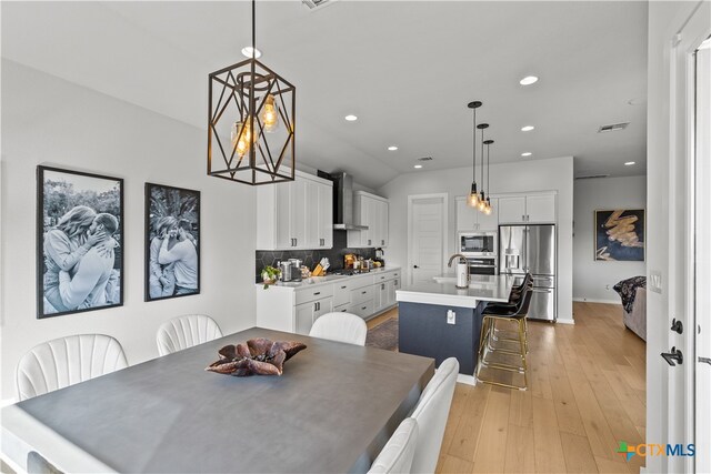 dining area with a chandelier, sink, and light hardwood / wood-style flooring