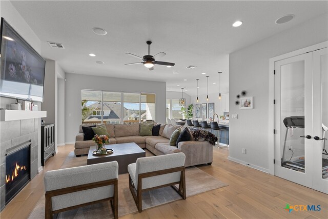 living room featuring ceiling fan, light hardwood / wood-style floors, and a fireplace