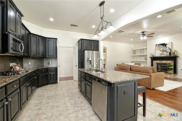 1108 Celtic Cv, Round Rock, TX 78681 - kitchen with stainless steel appliances, ceiling fan, light tile patterned floors, a kitchen island with sink, and stone countertops