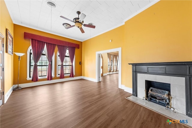 unfurnished living room featuring visible vents, crown molding, baseboards, wood finished floors, and a ceiling fan