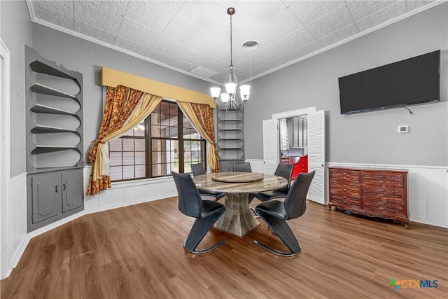 dining area featuring visible vents, built in shelves, an inviting chandelier, and wood finished floors