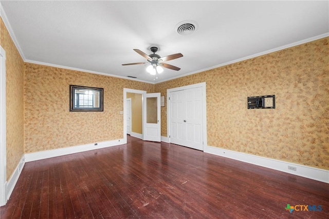 empty room featuring visible vents, wallpapered walls, baseboards, and hardwood / wood-style flooring