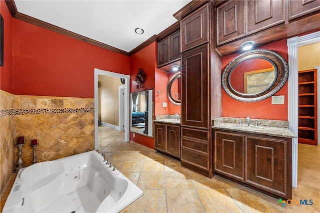 full bath with crown molding, a tub with jets, double vanity, and a sink