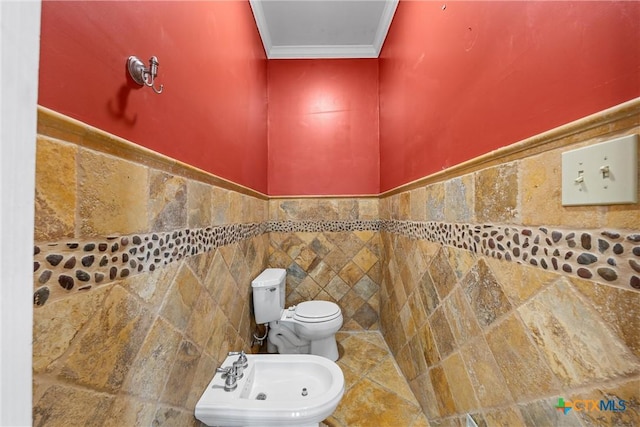 bathroom featuring toilet, a bidet, tile walls, wainscoting, and crown molding