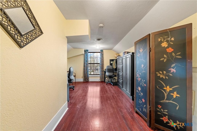 interior space with visible vents, baseboards, vaulted ceiling, a textured ceiling, and dark wood-style flooring