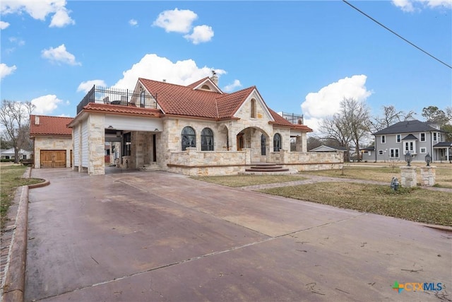 view of front of property featuring driveway, stone siding, an attached garage, a balcony, and a tiled roof