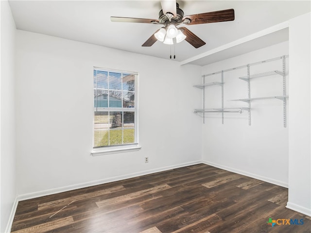 empty room with dark wood-style floors, baseboards, and a ceiling fan