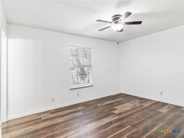 empty room with dark wood-type flooring, a ceiling fan, and baseboards