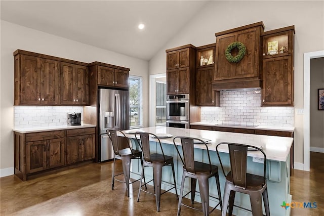 kitchen featuring decorative backsplash, a kitchen breakfast bar, stainless steel appliances, and a kitchen island