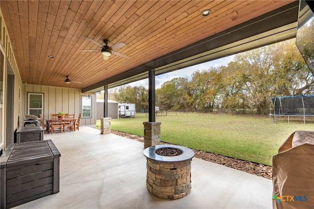 view of patio featuring ceiling fan, a trampoline, and an outdoor fire pit