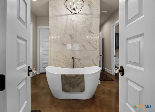 bathroom featuring a tub to relax in, concrete flooring, and a notable chandelier