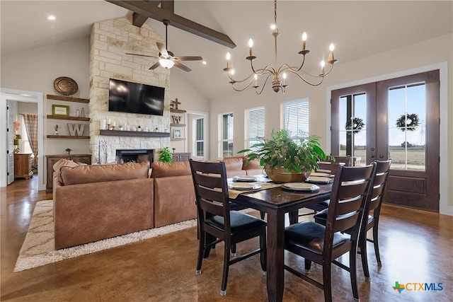 dining space with high vaulted ceiling, french doors, ceiling fan with notable chandelier, a stone fireplace, and beam ceiling