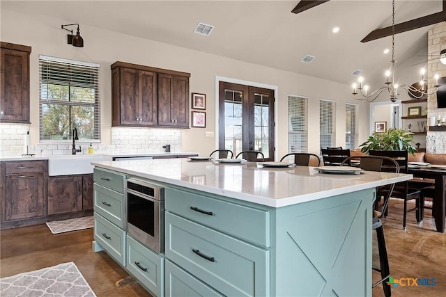 kitchen featuring decorative backsplash, vaulted ceiling with beams, a kitchen island, and a healthy amount of sunlight