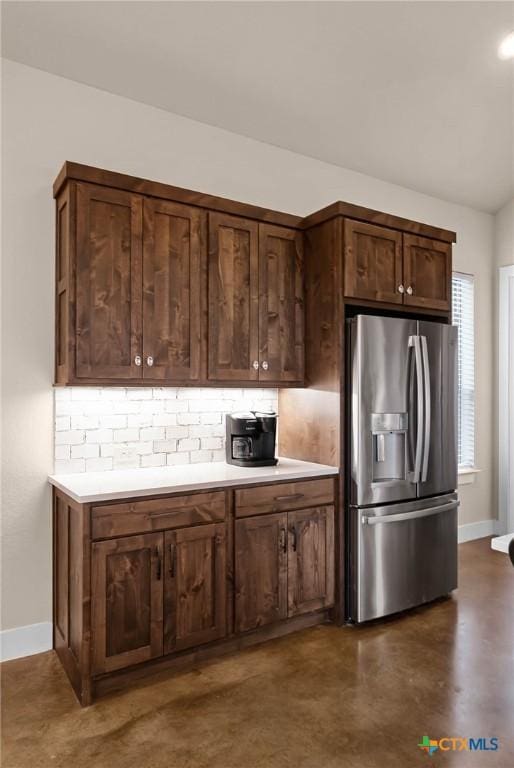 kitchen with decorative backsplash, stainless steel fridge, and dark brown cabinets