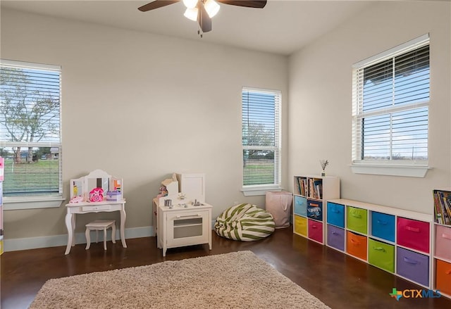 recreation room with a wealth of natural light, ceiling fan, and dark hardwood / wood-style floors