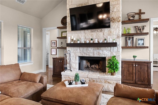 living room featuring hardwood / wood-style floors, a stone fireplace, and high vaulted ceiling