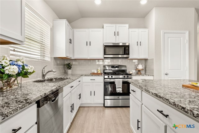 419 Agave Flats Dr, New Braunfels, TX 78130 - kitchen with appliances with stainless steel finishes, lofted ceiling, light wood-type flooring, white cabinetry, and tasteful backsplash