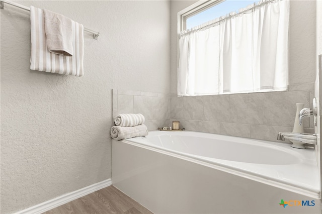 419 Agave Flats Dr, New Braunfels, TX 78130 - bathroom with a textured wall, a bath, and wood finished floors