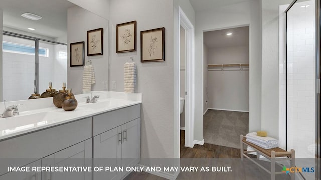 full bath featuring double vanity, a shower stall, a spacious closet, and a sink