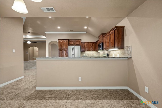 1722 Shadow Canyon Dr, Temple, TX 76502 - kitchen with appliances with stainless steel finishes, arched walkways, backsplash, light stone counters, and vaulted ceiling