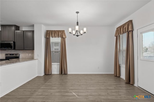 kitchen featuring stainless steel appliances, plenty of natural light, dark brown cabinetry, and light stone counters