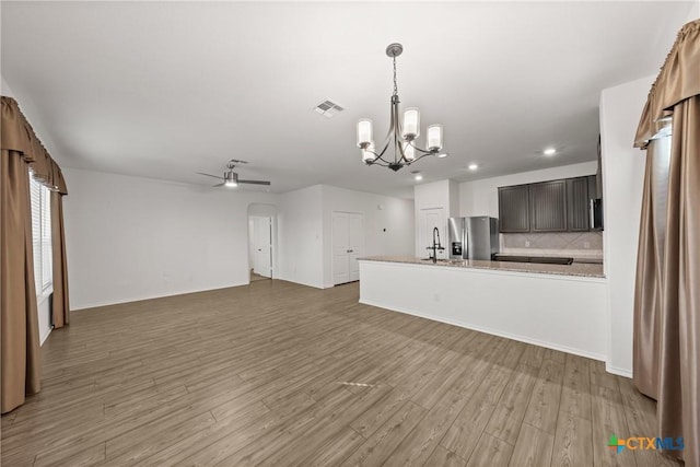 kitchen featuring hardwood / wood-style flooring, ceiling fan with notable chandelier, backsplash, and stainless steel fridge with ice dispenser