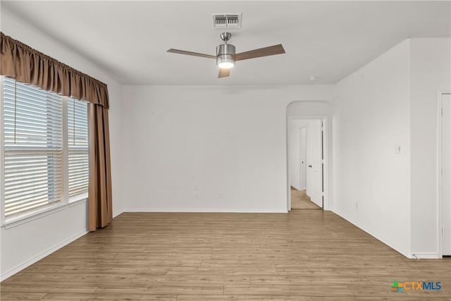 unfurnished room with a wealth of natural light, ceiling fan, and light wood-type flooring