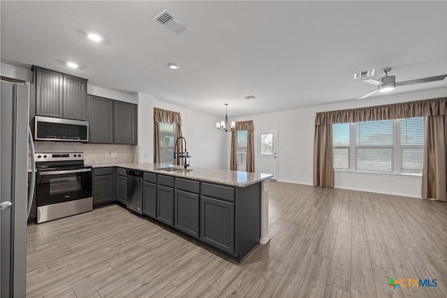 kitchen with pendant lighting, sink, appliances with stainless steel finishes, light hardwood / wood-style floors, and kitchen peninsula