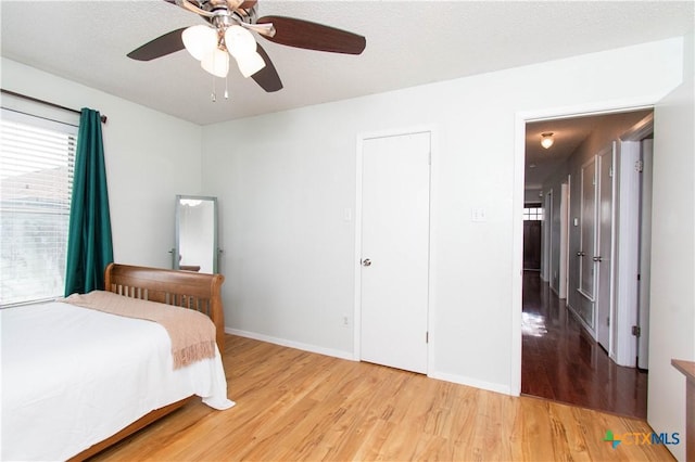 bedroom featuring light wood-style floors, a ceiling fan, and baseboards