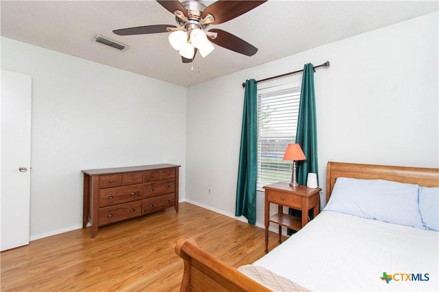 bedroom featuring visible vents, light wood finished floors, baseboards, and ceiling fan