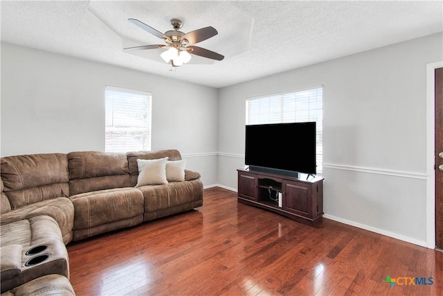living area featuring baseboards, a textured ceiling, a ceiling fan, and dark wood-style floors